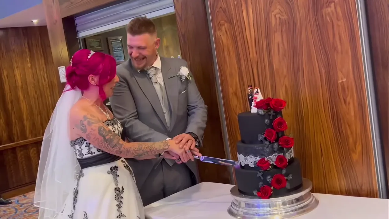 Couple cutting a black cake with red roses